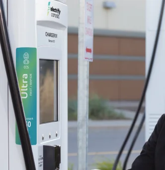 Woman looking at Electrify Canada charger display with teal Ultra-Fast charging label